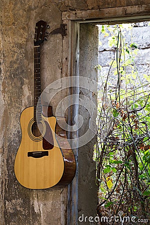 Guitar hanged on the wall in the broken house Stock Photo