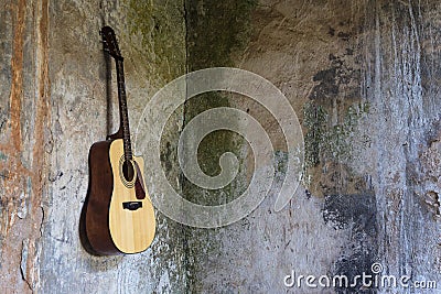 Guitar hanged on the wall in the broken house. Stock Photo