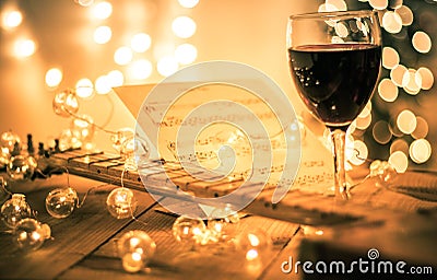 Guitar with instrumental sheet music and soft lights and red wine for Christmas holiday, split tone Stock Photo