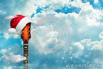 Guitar in a Santa Hat. Cloudy sky. New Year`s banner. Congratulations to musicians, music stores. Copy space. Place for your text Stock Photo