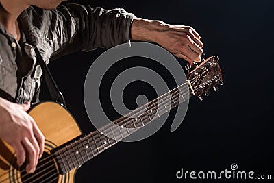 Guitarist, music. A young man plays an acoustic guitar on a black isolated background Stock Photo