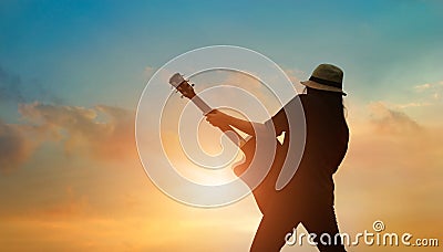 Guitarist playing acoustic guitar on the colorful cloudscape sunset Stock Photo