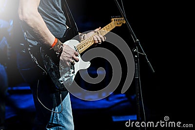 The guitarist plays the electric guitar. Guitar neck close-up on a concert of rock music in the hands of a musician. Stock Photo