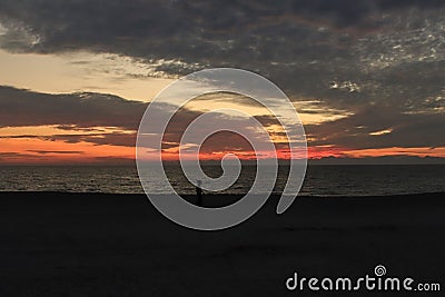 Orange Gulf of Mexico sunset with pedestrian silhouette on beach Stock Photo