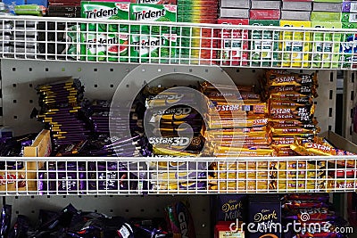 Gum, Mint, Nestle Dairy milk, Bounty, Mars, 5Star chocolates candy bar displayed on a shelf inside a supermarket. Chocolate Sweets Editorial Stock Photo