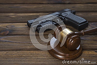 A gun and a hammer judge on the background of a wood texture table. Stock Photo