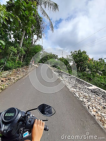 POV in over head shot from a motorbike driving on a village road. Editorial Stock Photo