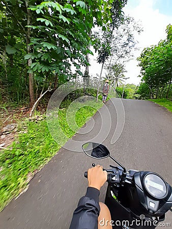 POV in over head shot from a motorbike driving on a village road. Editorial Stock Photo