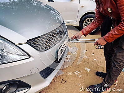 Man using a riveting locking tool to affix a tamper proof HSRP high security registeration plate to a maruti swift car Editorial Stock Photo