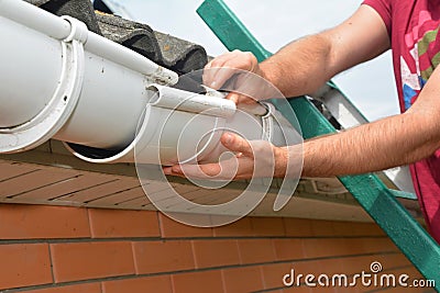 Gutter pipeline installation. Roofer contractor installing and repair rain gutter. Guttering repair Stock Photo