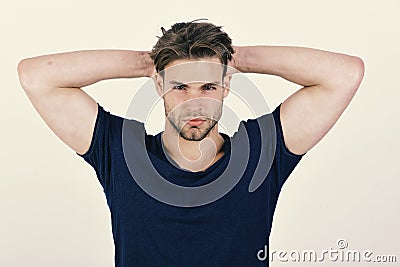 Guy with bristle in dark blue tshirt. Macho with confident face holds hands behind head. Stock Photo