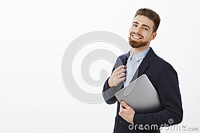 Guy can deal with any task feeling self-assured and pleased touching suit holding laptop in arm standing half-turned Stock Photo