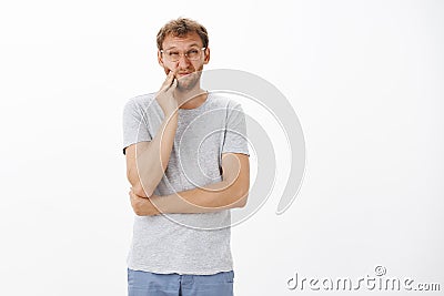 Guy cannot find time visit dentist. Displeased intense charming european male with bristle squinting and wrinkling nose Stock Photo