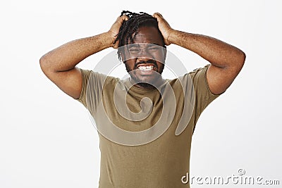 Guy cannot hold negative emotions inside. Depressed desperate african american man in olive t-shirt, holding hands on Stock Photo