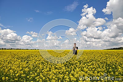 The guy closes his nose and sneezes in the flowering yellow field. Alergy on pollen Stock Photo