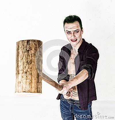 Guy with crazy joker face, green hair and idiotic smile. carnaval costume. holding hammer for cricket Stock Photo