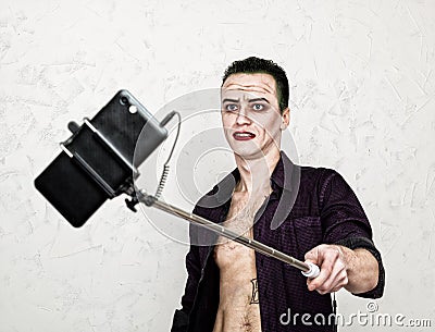 Guy with crazy joker face, green hair and idiotic smile. carnaval costume. making selfy photo Stock Photo