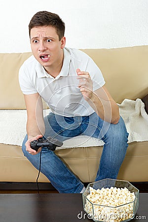 Guy eating popcorn with joystick for game console Stock Photo