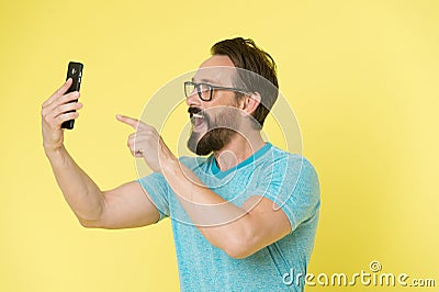 Guy eyeglasses cheerful pointing at smartphone. Man happy user interact application for smartphone. Guy bearded interact Stock Photo