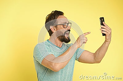 Guy eyeglasses cheerful pointing at smartphone. Man happy user interact application for smartphone. Guy bearded interact Stock Photo