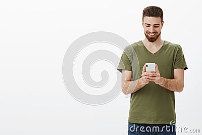 Guy feeling delighted taking awesome pics with camera on smartphone holding mobile phone looking at device screen with Stock Photo