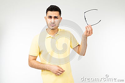 Guy feels pain in his eyes removing his glasses for vision on a white background Stock Photo