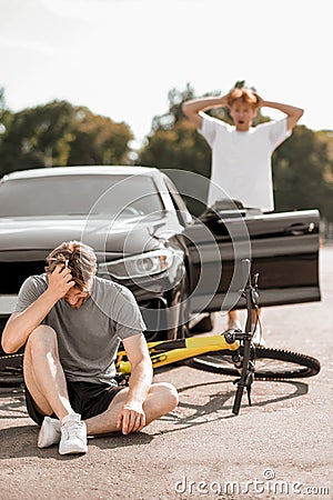 Guy felling off bike and worried driver Stock Photo