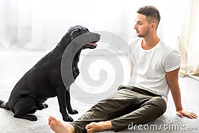 Guy freelancer with his dog labrador playing at home Stock Photo