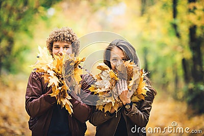 Guy and girl hold in their hands lot of autumn maple leaves and close their faces. Stock Photo
