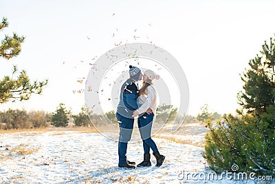 The guy with the girl kiss in the winter in the woods against the background of falling candy. Romantic winter atmosphere Stock Photo