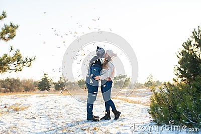 The guy with the girl kiss in the winter in the woods against the background of falling candy. Romantic winter atmosphere Stock Photo