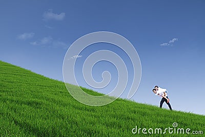 Guy giving piggyback ride on hill under blue sky Stock Photo