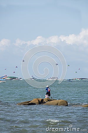 Guy has a quiet moment by himself, fishing on the rock island, Pattaya. Editorial Stock Photo