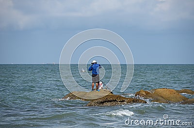Guy has a quiet moment by himself, fishing on the rock island, Pattaya. Editorial Stock Photo