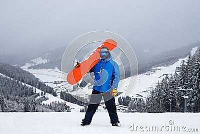 The guy hold on the shoulder orange snowboard in winter Stock Photo