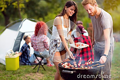 Guy and lassie putting grilled skewers on plate Stock Photo