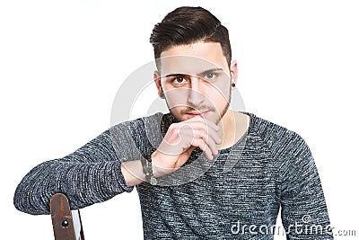 guy look at camera with serious and pensive look at camera in a haunting way of the macho while sit with hand at chin and being in Stock Photo