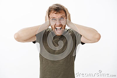 Guy lose temper being with loud noises at night yelling out loud with angry outrage expression covering ears with Stock Photo