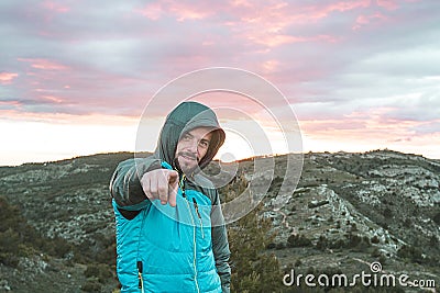 Guy on the mountain pointing at the camera. Mountaineer making a positive gesture Stock Photo