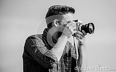 Guy outdoors blue sky background. Handsome blogger guy traveler retro camera. Reporter taking photo. Manual settings Stock Photo