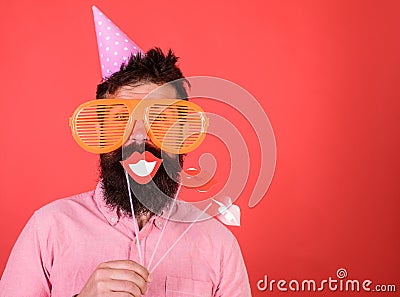 Guy in party hat celebrate, posing with photo props. Hipster in giant sunglasses celebrating. Man with beard on cheerful Stock Photo