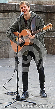 Guy is playing acoustic guitar outside in Milan Editorial Stock Photo