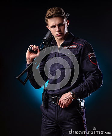 A guy in a police uniform with a short barreled automatic rifle with a telescopic sight takes aim. english translation Stock Photo