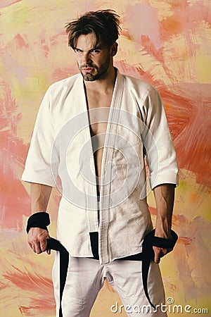 Guy poses in white kimono holding black belt Stock Photo