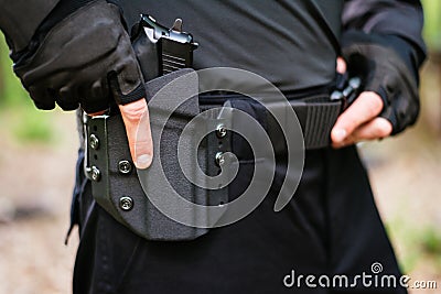 The guy puts the gun in the holster close-up Stock Photo