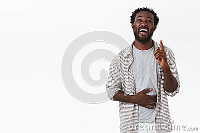 Guy recalled funny joke, raising one finger and looking up, holding belly as laughing out loud, smiling and chuckling Stock Photo