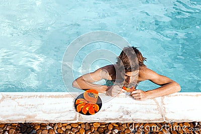 Guy relaxing in pool and eating papaya Stock Photo