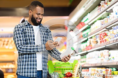 Guy Scanning Product Via Phone Doing Grocery Shopping In Supermarket Stock Photo