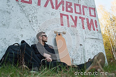 The guy is sitting next to the longboard, the inscription on the wall of a Happy journey Stock Photo