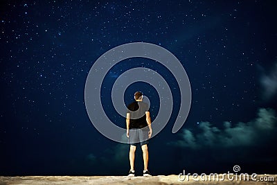 The guy is standing at night looking at the stars into the distance, rear view Stock Photo